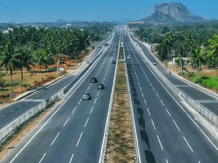 Modern highway surrounded by greenery and hills, representing connectivity and infrastructure development in Karnataka.